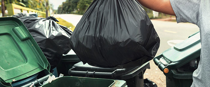 photo d'une personne qui jette son sac poubelle dans la poubelle